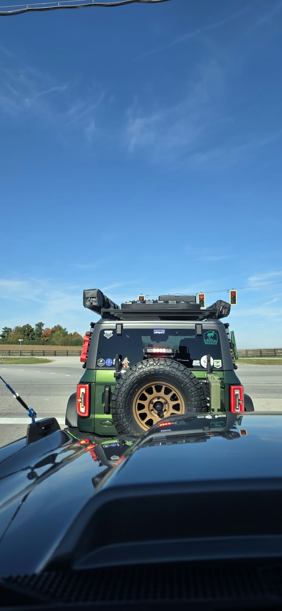 Green Ford Bronco on the road, rear view with spare tire on the tire carrier